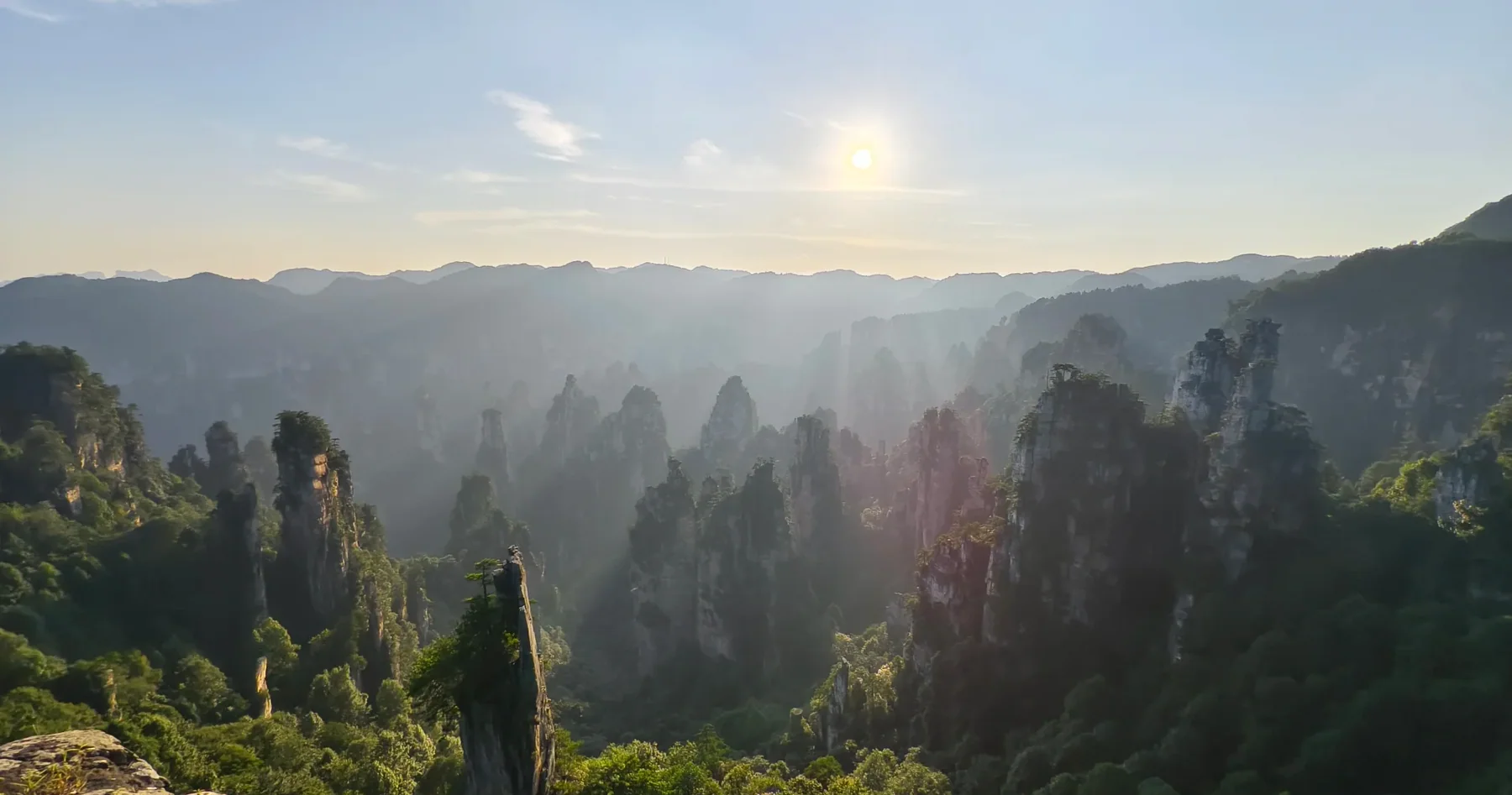 A wide view of sandstone pillars fading into the evening light in Zhangjiajie