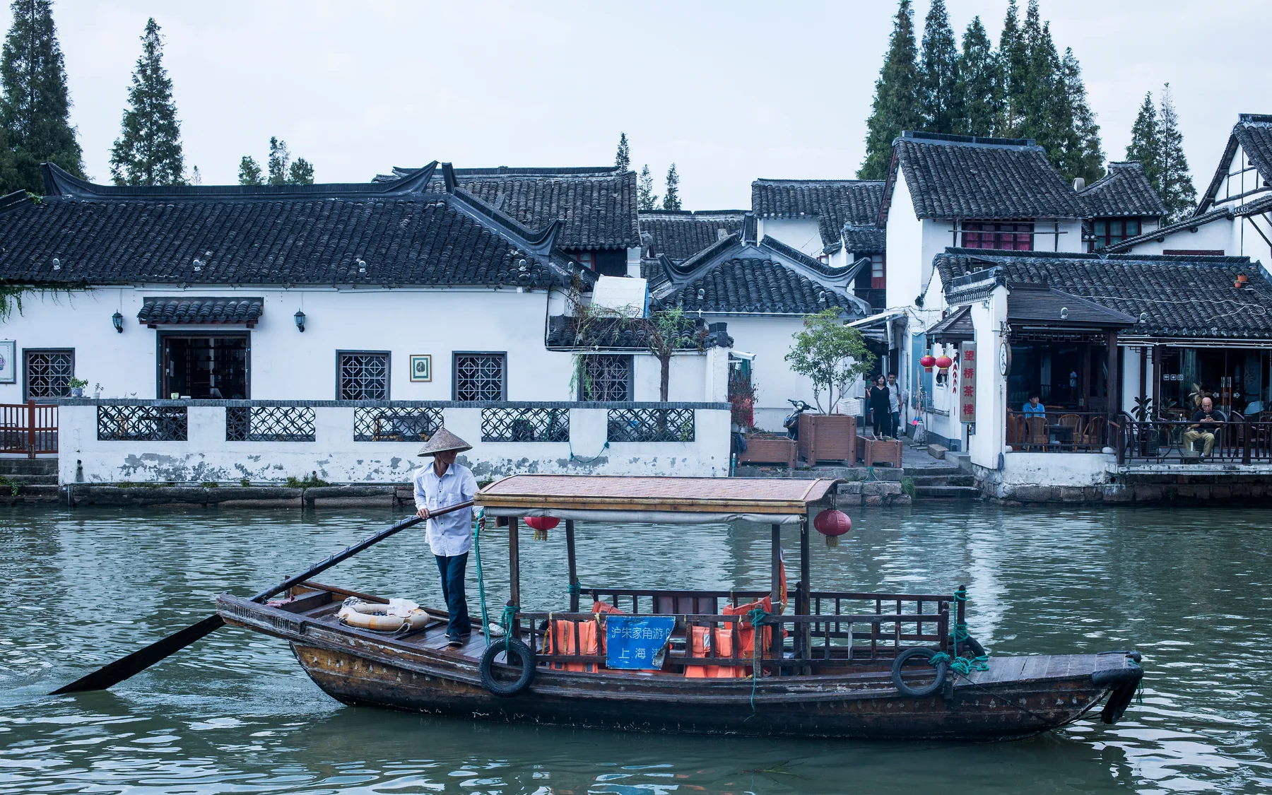 A working boat passing white-walled canal buildings, keeping transport and labor inside the Jiangnan image