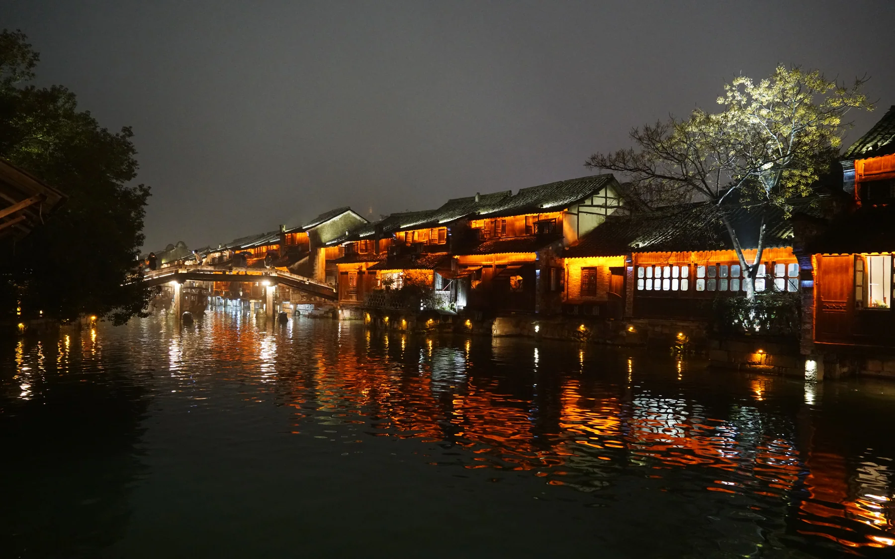 A Jiangnan water settlement at night showing how canal edges become lived evening space